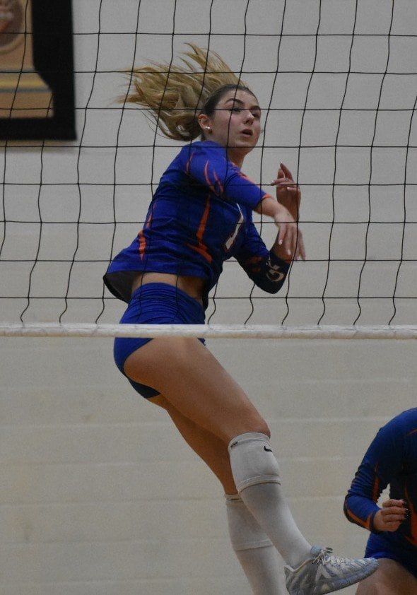 Presley Meyer setting a volleyball during a high school game, focused and determined.